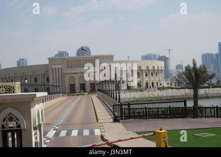 Sharjah is the third largest emirate in the United Arab Emirates. Lots of mighty skyscrapers with glass facades, palm trees, mosques. Nice garden, bay Stock Photo