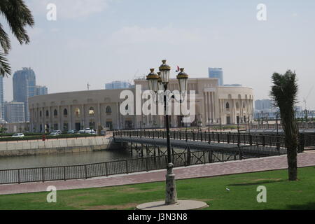 Sharjah is the third largest emirate in the United Arab Emirates. Lots of mighty skyscrapers with glass facades, palm trees, mosques. Nice garden, bay Stock Photo