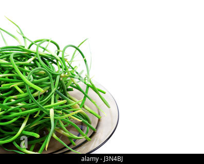 Fresh garlic scapes on glass plate. Isolated on white background with copyspace Stock Photo