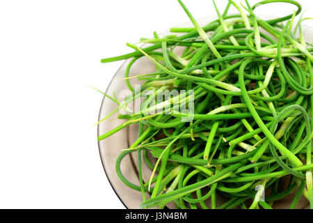 Fresh garlic scapes on glass plate. Isolated on white background with copy space. Stock Photo