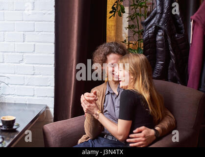 A young couple sitting embraced and feeling happy and laughing at cafe Stock Photo