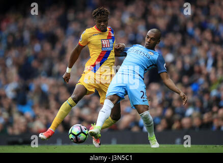 Manchester City's Fernandinho and Crystal Palace's Wilfried Zaha (left) battle for the ball during the Premier League match at the Etihad Stadium, Manchester. Stock Photo