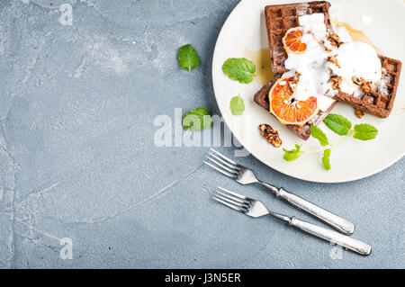 Belgian soft waffles with blood orange, cream, marple syrup and mint  on white plates  Stock Photo