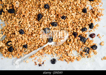 Homemade oat, cherry and coconut granola over baking paper with spoon,  Stock Photo