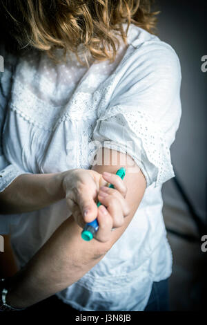 Diabetes. Woman making insulin injection into her arm with autoinjector ...
