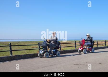 Wheelchair user at Lytham St Annes on Sea, Lancashire.  UK Weather. 7th May, 2017. Senior, Pensioner disabled person using mobility scooter on bright, sunny start to the day as residents asnd holiday makers enjoy the seafront and promenade in this Lancashire town looking out towards Irish sea. and Ribble Estuary.  Credit; MediaWorldImages/AlamyLiveNews Stock Photo