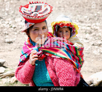 Close up portrait of a smiling Quechua woman dressed in colourful traditional handmade outfit and carrying her baby in a sling. October 21, 2012 - Pat Stock Photo
