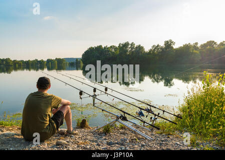 Fishing adventures, carp fishing. Angler is fishing with carpfishing technique in freshwater, in a beautiful summer day Stock Photo