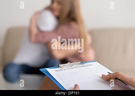 Close up of psychologist writing notes about couple on session Stock Photo