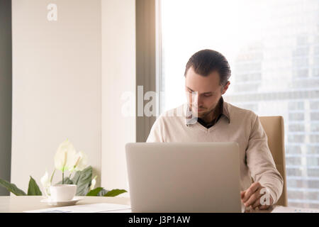 Young successful businessman working at office desk using laptop Stock Photo