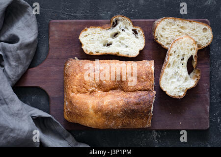 Ciabatta bread sliced on wooden cutting board. Top view Stock Photo