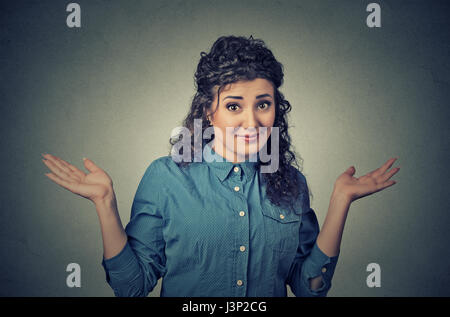 Portrait dumb looking woman arms out shrugs shoulders who cares so what I don't know isolated on gray wall background. Negative human emotion, facial  Stock Photo