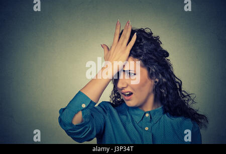 Regrets wrong doing. Closeup portrait silly young woman, slapping hand on head having duh moment isolated on gray background. Negative human emotion f Stock Photo