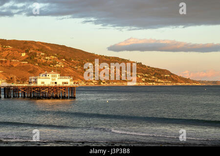 Sun is about to set at Malibu Pier casting warm lights to the hills, Malibu California Stock Photo