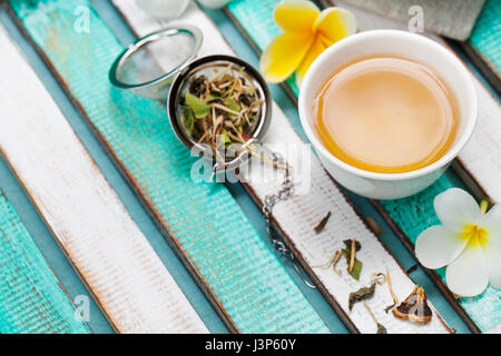 Herbal green tea in white cup with dry tea and fresh flowers. Copy space. Stock Photo