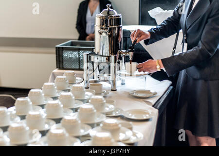 Abstract blurred many rows of coffee or tea cups with coffee dispenser business people taking one Stock Photo