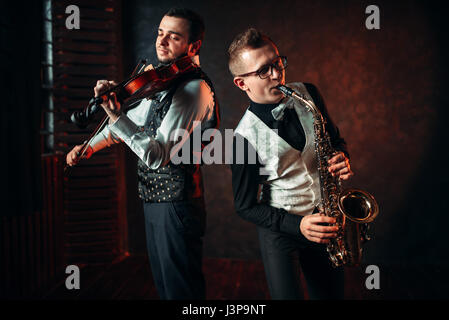 Saxophonist and violinst playing classical melody, musical duet. Jazz-man and fiddler Stock Photo