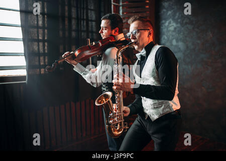 Sax man and fiddler duet playing classical melody. Jazz man and violinist Stock Photo