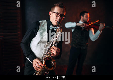 Saxophonist and violinst playing classical melody, musical duet. Jazz-man and fiddler Stock Photo