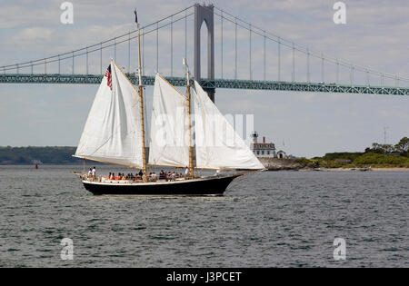 The sailing vessel 'Aquidneck' passes the Clayborn Pell (Jamestown) Bridge and Rose Island Light off Newport, Rhode Island, USA Stock Photo