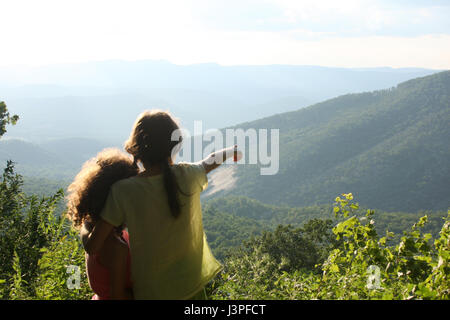 Two little girls in front of mountain landscape in summertime Stock Photo