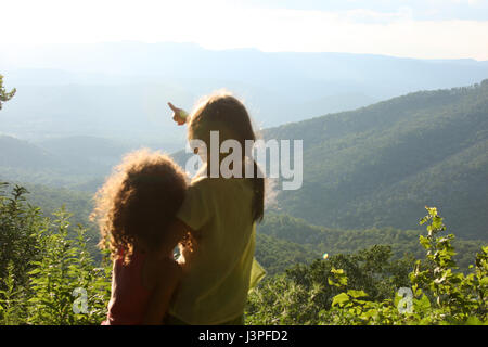 Two little girls in front of mountain landscape in summertime Stock Photo