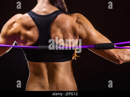 Close-up of athletes performing back exercises with a resistance group against a dark background Stock Photo