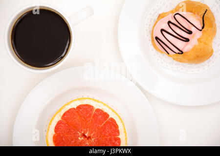 Closeup of a grapefruit versus cake with black coffee on white background Stock Photo
