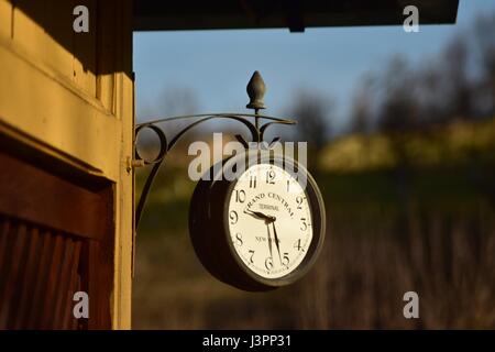 Vintage outdoor wall clock hang on the cabin with hill in the background Stock Photo