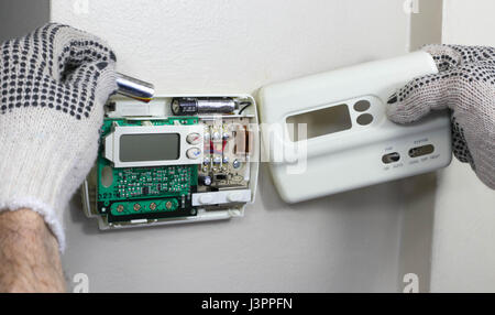 HVAC Technician Installing Batteries in Thermostat Stock Photo