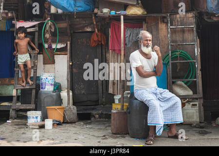 Elderly man sitting outside his home, Mumbai, India Stock Photo