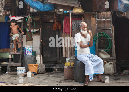 Elderly man sitting outside his home, Mumbai, India Stock Photo