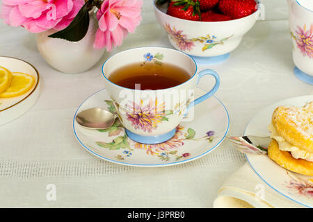 Cup of tea served in a vintage fine china tea cup with fresh cream cakes. Stock Photo