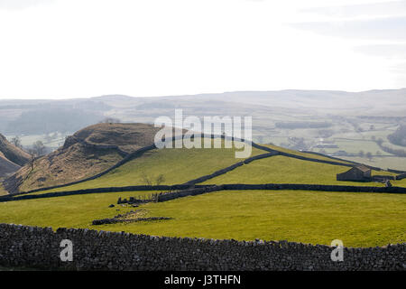 Conistone Landscape showing dry stone walls a stone barn and views across the Wharfe valley with a grey hazy sky. Stock Photo