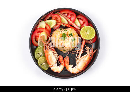 Fried Jasmine rice with large prawns in heart shape topped sliced cucumber,tomato and green lemon served on black dish ,isolated on white background. Stock Photo