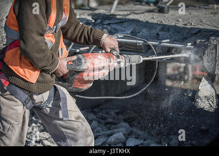 man using a jackhammer to drill into wall. professional worker in construction site Stock Photo