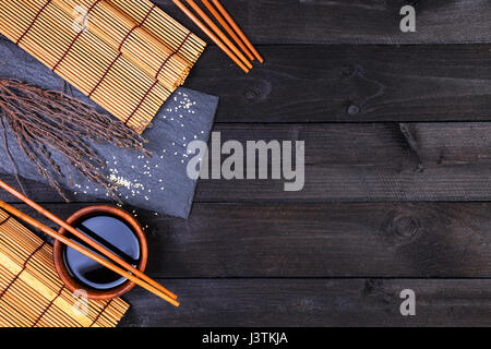 Sushi chopsticks and soy sauce on black background. Top view with copy space. Stock Photo