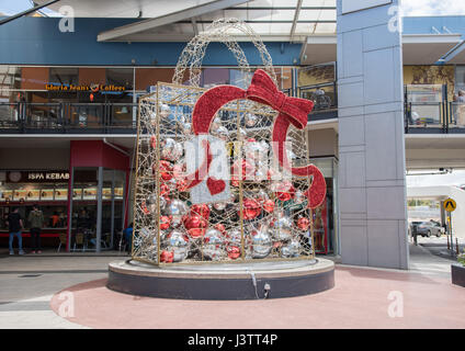 Large metallic silver and red package with ornaments and bow to celebrate Christmastime near urban shopping mall in Perth, Western Australia. Stock Photo
