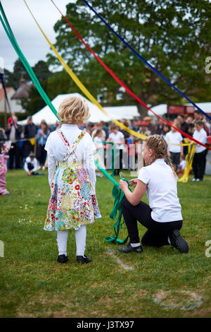 A young, blonde girl stands holding a May pole ribbon before dancing on May Day. Stock Photo