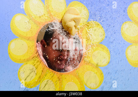 A wet sponge hits a man in the face through a peep board. Stock Photo