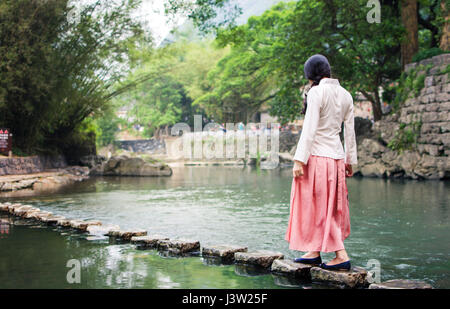 Girl walking on small stone bridge in the river Stock Photo