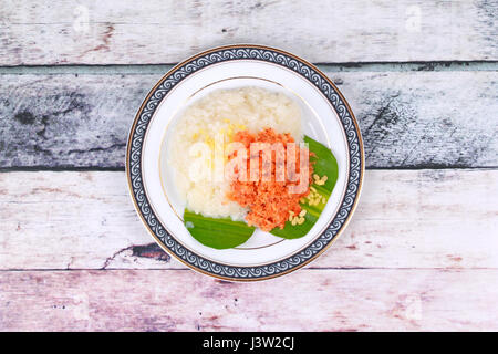 Thai dessert ,Sticky rice in coconut milk with stir-fried grated coconut and shrimp served topped coconut milk on Thai pattern disk Stock Photo