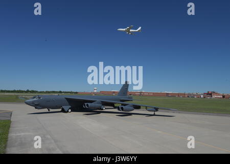 Boeing B-52H, 60-0005, poses in front of Oklahoma City Air Logistics Complex Bldg. 3001 following major overhaul while a Boeing E-6B TACAMO aircraft flies overhead on May 1, 2017, Tinker Air Force Base, Oklahoma. OC-ALC is responsible for depot level maintenance of both aircraft fleets with a large portion of the work taking place in the building shown behind. (U.S. Air Force photo/Greg L. Davis) Stock Photo