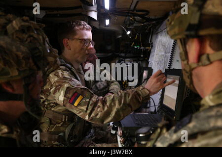 British Army 2nd Lt. David Cahill, center, of the 1st Armored Medical Regiment, Queens Royal Hussars briefs British soldiers on mission details while conducting defensive operations during Saber Junction 17 at the Hohenfels Training Area, Germany, May 2, 2017. Saber Junction 17 is the U.S. Army Europe’s 2nd Cavalry Regiment’s combat training center certification exercise, taking place at the Joint Multinational Readiness Center in Hohenfels, Germany, Apr. 25-May 19, 2017. The exercise is designed to assess the readiness of the regiment to conduct unified land operations, with a particular emph Stock Photo