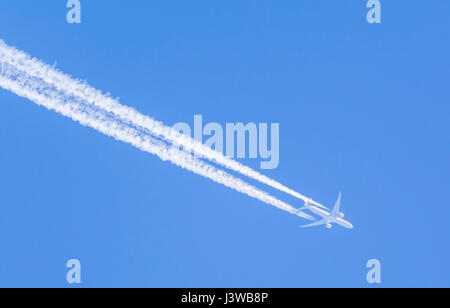 Contrails from a jet plane flying against blue sky. Stock Photo