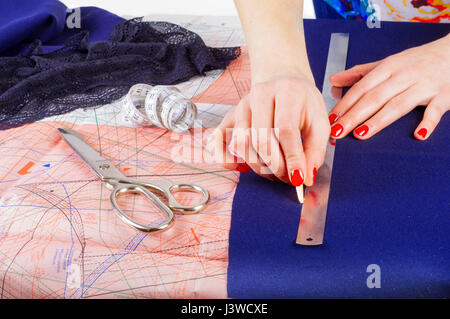 Close up hands of a fashion designer at work with cloth fabric. Female hands at work with ruler for new cloth. Stock Photo