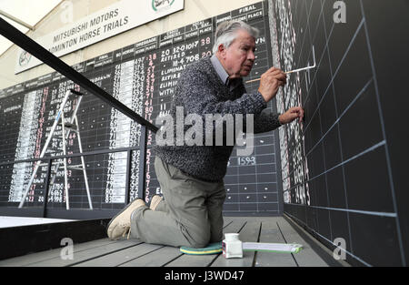 Scoreboard writer Gerald Kington, paints the scores from the show jumping on the main scoreboard during day five of the 2017 Badminton Horse Trials. Stock Photo