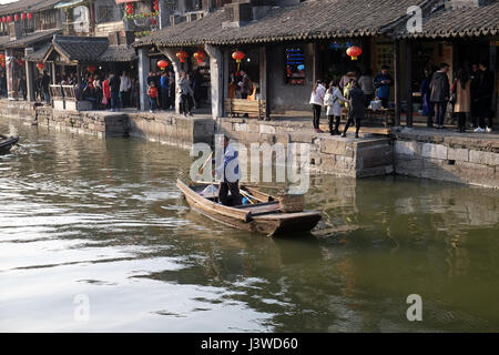 Man in a ancient wooden boat on the water canals of Xitang Town in Zhejiang Province, China, February 20, 2016. Stock Photo