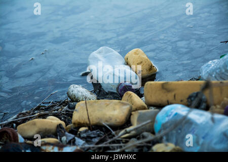 An image of rubbish that's been fly tipped, with the focus on an empty drinks bottle. It represents environmental issues such as plastic pollution. UK Stock Photo