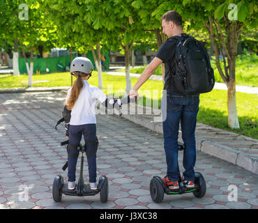 Young father and daughter riding electric mini hoverboard in park Stock Photo